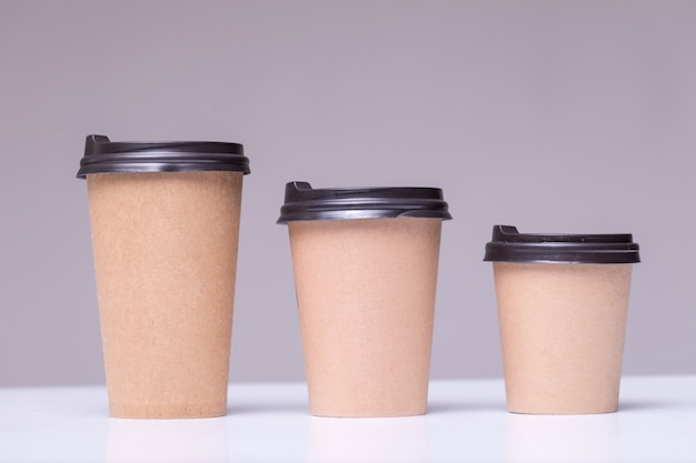 Free photo covered paper coffee cups different sizes isolated on gray