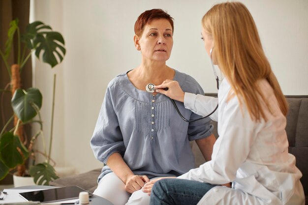 Covid recovery center female doctor checking elder patient's heartbeat