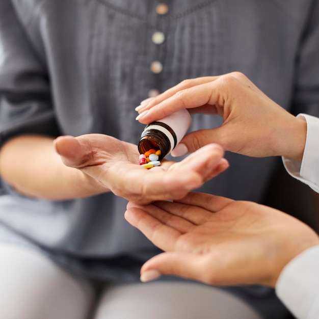 Covid recovery center female doctor giving elder patient pills in hand