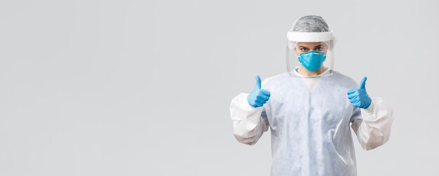 Covid19 preventing virus health healthcare workers and quarantine concept Determined confident doctor nurse in personal protective equipment respirator and gloves show thumbsup fight corona