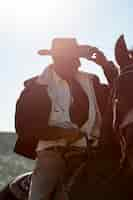 Free photo cowboy silhouette with horse against warm light