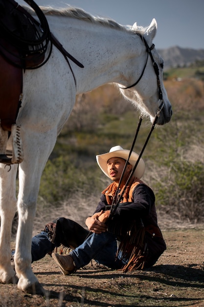 Free photo cowboy silhouette with horse against warm light