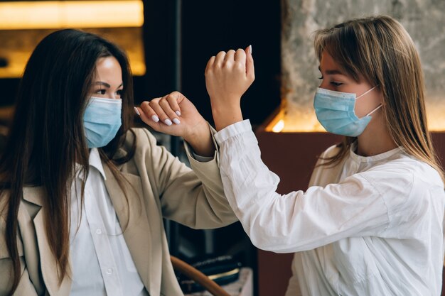 Coworkers in protective masks giving high five with elbows