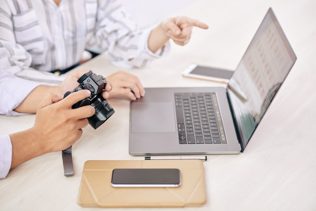 Coworking photographers with gadget at desk