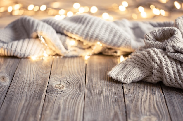 Cozy background with knitted element and bokeh lights on a wooden surface