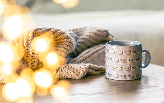 Free photo cozy background with shiny gray cup bokeh lights and knitted element