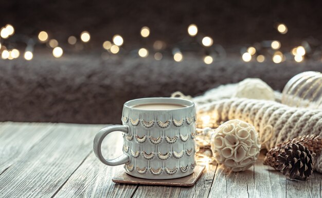 Cozy Christmas background with a beautiful cup and decor details on a blurred background with bokeh.