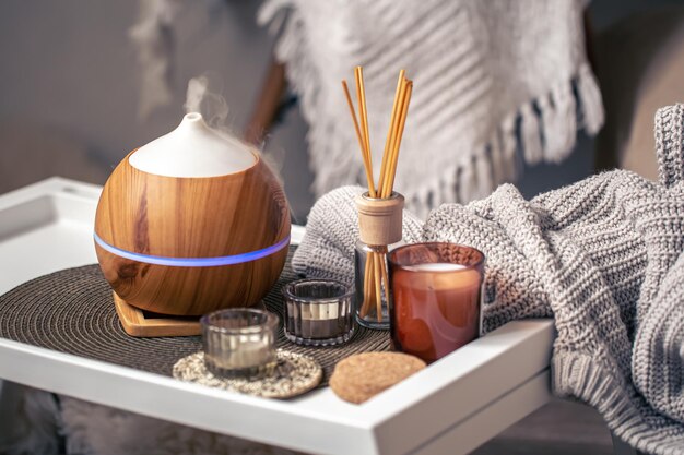 A cozy composition with an aroma diffuser and candles in a home interior