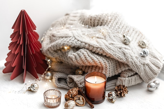 Free photo cozy composition with burning candles knitted element and decorative details