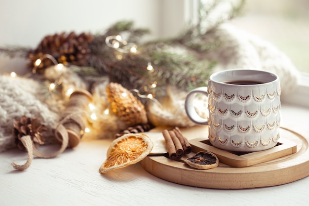 Cozy composition with a Christmas cup with a hot drink and cinnamon on a blurred background. Home winter coziness concept.