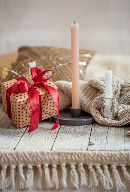 Cozy festive still life with a gift and a candle on a wooden table. The festive concept.