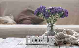 Free photo cozy home composition with a bouquet of blue chrysanthemums in a glass vase and the decorative word home.