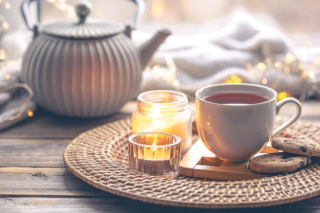 Cozy home composition with a cup of tea candles and a teapot