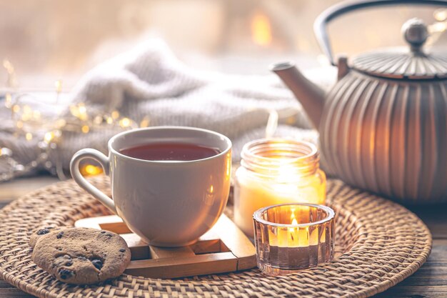 Cozy home composition with a cup of tea candles and a teapot