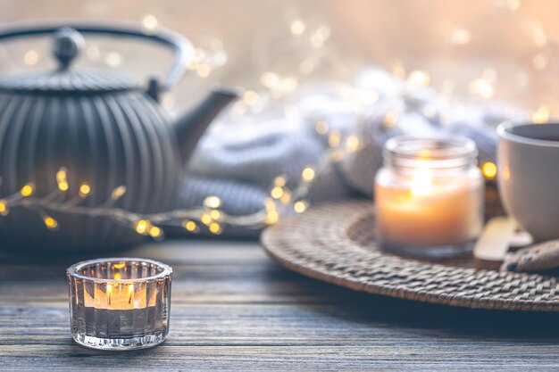 Free photo cozy home composition with a cup of tea candles and a teapot