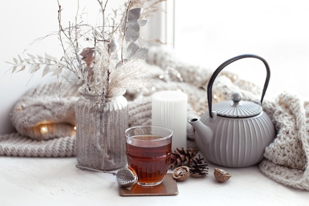 Cozy scandinavian composition with teapot a glass of tea and decor details