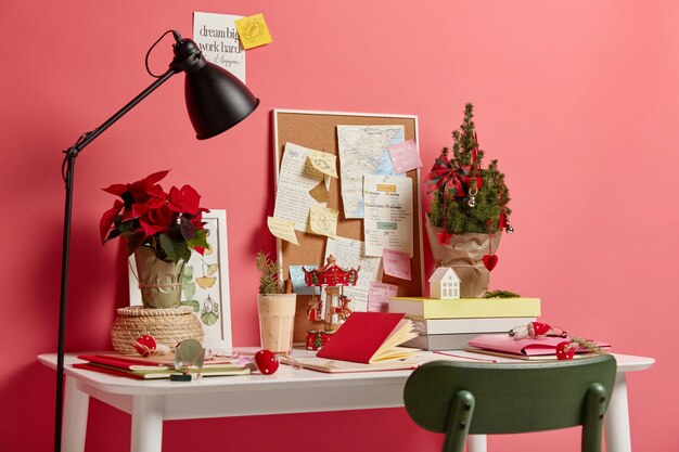 Free Photo cozy working space with no people. white desk with notepads, lamp, small decorated christmas fir symbolizing coming holiday