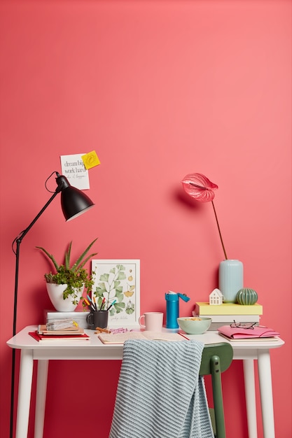 Free Photo cozy workplace with different things. beautiful calla liles in vase, pile of books, opened diary with written notes