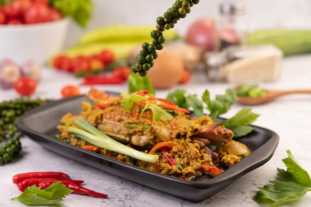 Crab stir-fried curry powder on a black plate on the cement floor.