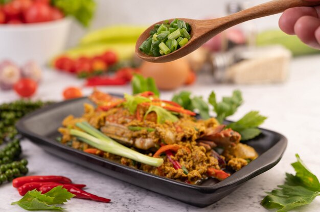 Crab stir-fried curry powder on a black plate on the cement floor.