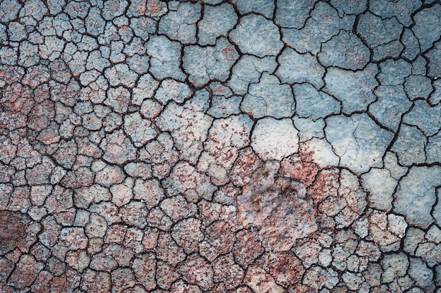 Cracked blue wall with red sand on it