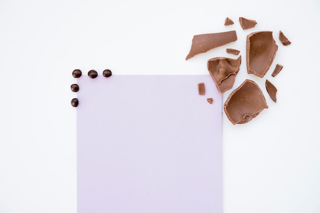 Free Photo cracked chocolate with blank paper on table 