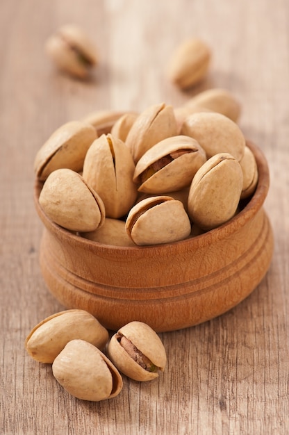 Cracked and dried pistachio nuts in a wooden bowl