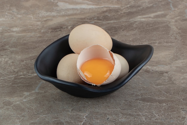 Free photo cracked raw egg in black bowl