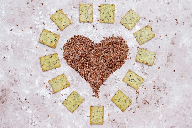 Crackers in shape of heart from linen seeds with olive oil,linen seeds and greens,top view