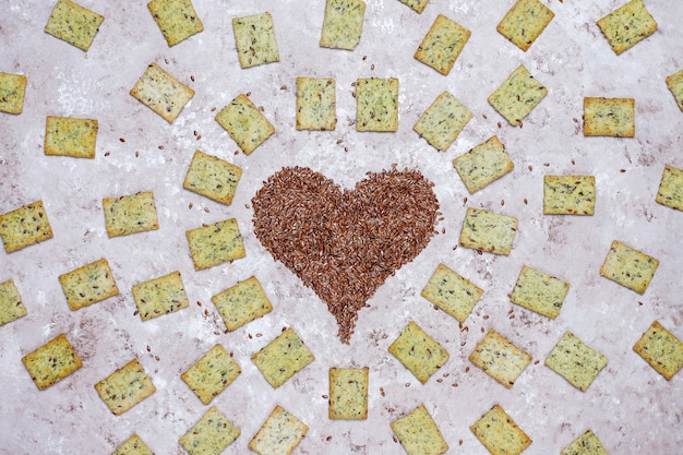 Crackers in shape of heart from linen seeds with olive oil,linen seeds and greens,top view