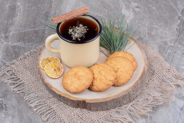 Crackers on a wooden board with lemon slices and a cup of glintwine