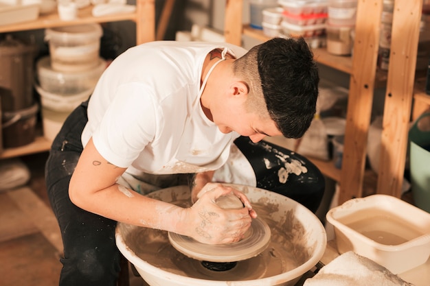 Free photo craftsman making vase from fresh wet clay on pottery wheel