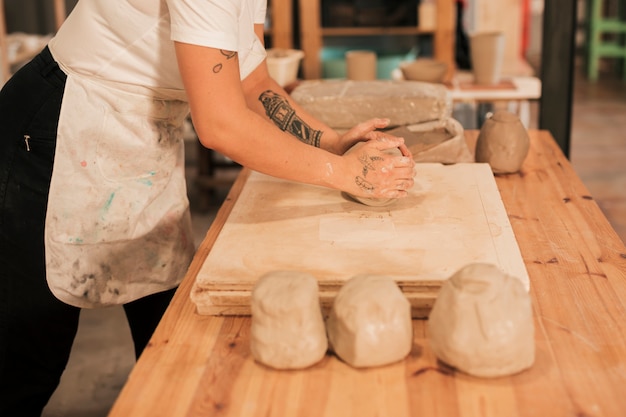 Craftswoman kneading the clay on wooden board over the table