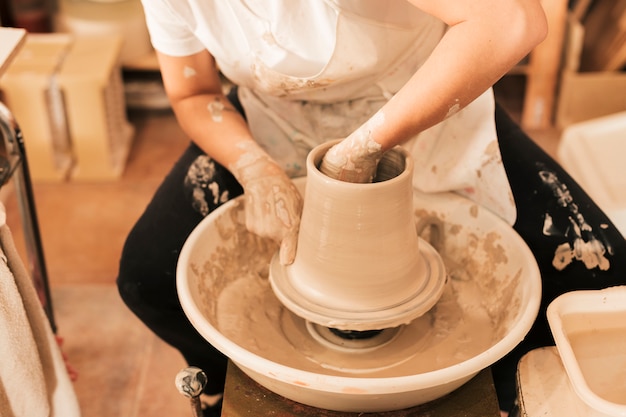 Craftswoman potter in apron at work on wheel