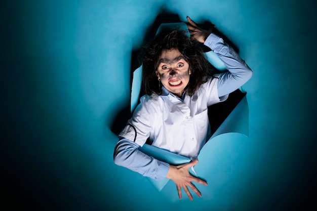 Free photo crazy silly biochemist with dirty face and messy hairstyle grinning creepy at camera after laboratory explosion. mad goofy scientist with exploded hair and smoky face after chemical experiment.