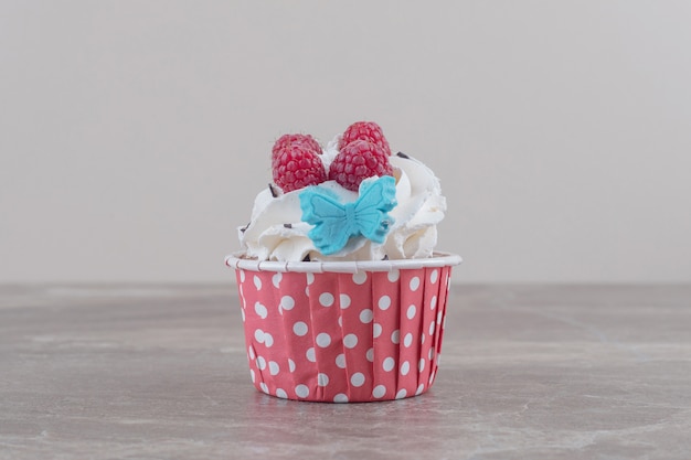 A cream and berry topped cupcake on marble 