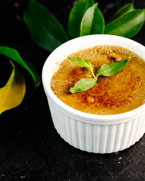 Cream brule in white bowl with mint leaves.