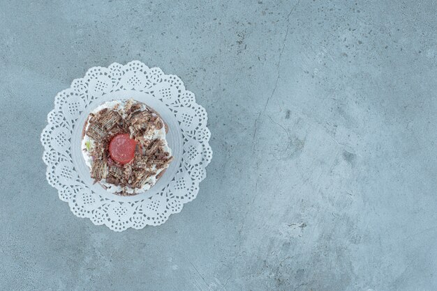 Cream and marmelade topped cake on a doily on marble background. High quality photo