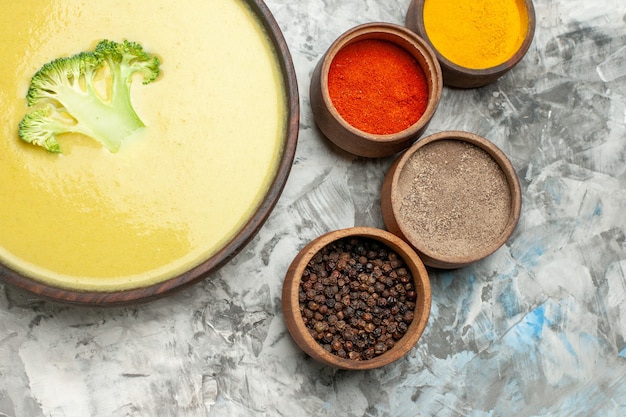 Free Photo creamy broccoli soup in a brown bowl and different spices on gray table