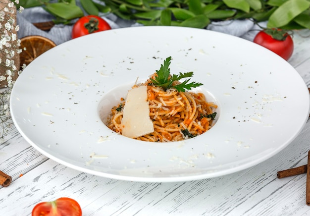 Free photo creamy carrot spaghetti with tomato, garnished with parsley and parmesan