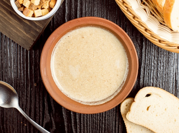 Creamy mushroom soup in pottery bowl with bread crackers. 