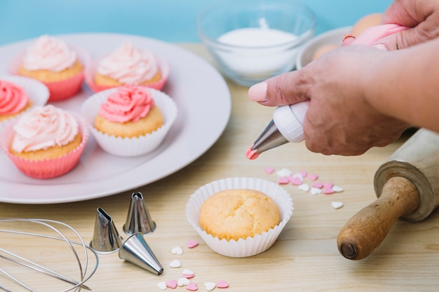 Creamy vanilla frosting being swirled onto individual sized cup cakes