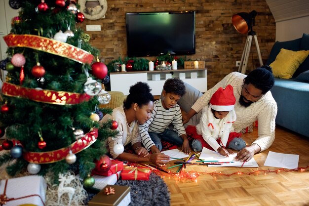 Creative black family coloring on the paper while spending Christmas day at home