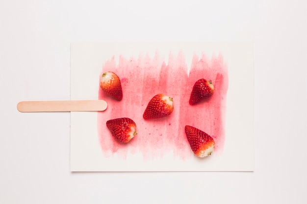 Creative composition of popsicle from fragrant strawberry on stick