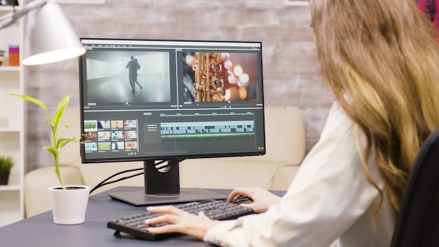 Free photo creative female filmmaker working on post production of a movie from home. boyfriend in the background.