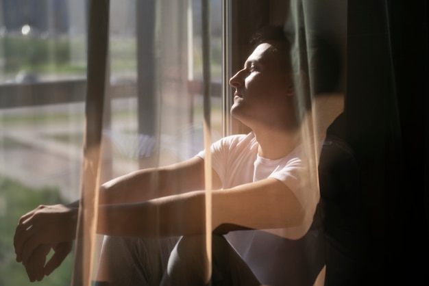 Creative portrait of man with curtains and shadows from window