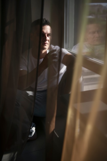 Free Photo creative portrait of man with curtains and shadows from window