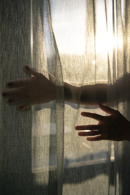 Free photo creative view of hands with curtains and shadows from window