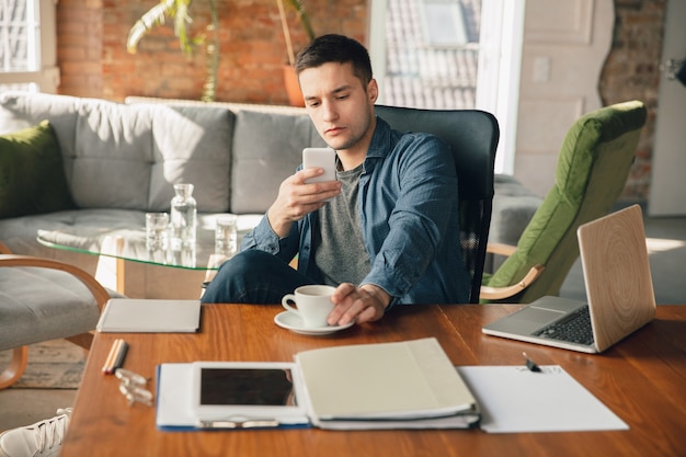 Free photo creative workplace - organized work space as you like for inspiration. man working in office in comfortable attire, relaxed position and messy table. choose atmosphere you want - ideal clear or chaos.