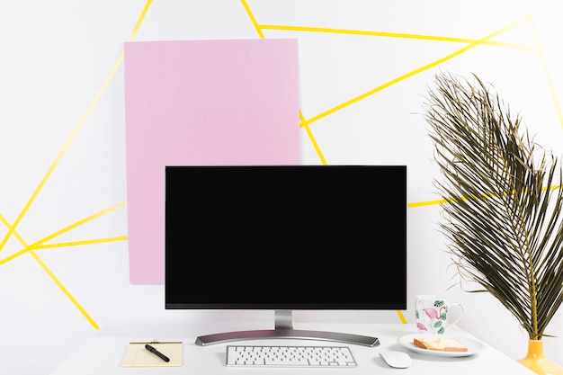 Free photo creative workplace with monitor and palm leaf